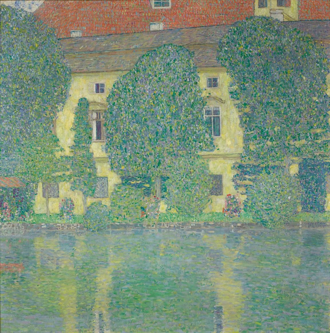 Hinter drei Bäumen sieht man ein Haus an einem See 