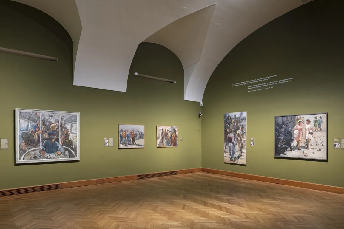 Ausstellungsraum mit gewölbter Decke und moosgrünen Wänden, darauf vage Bilder von Menschen