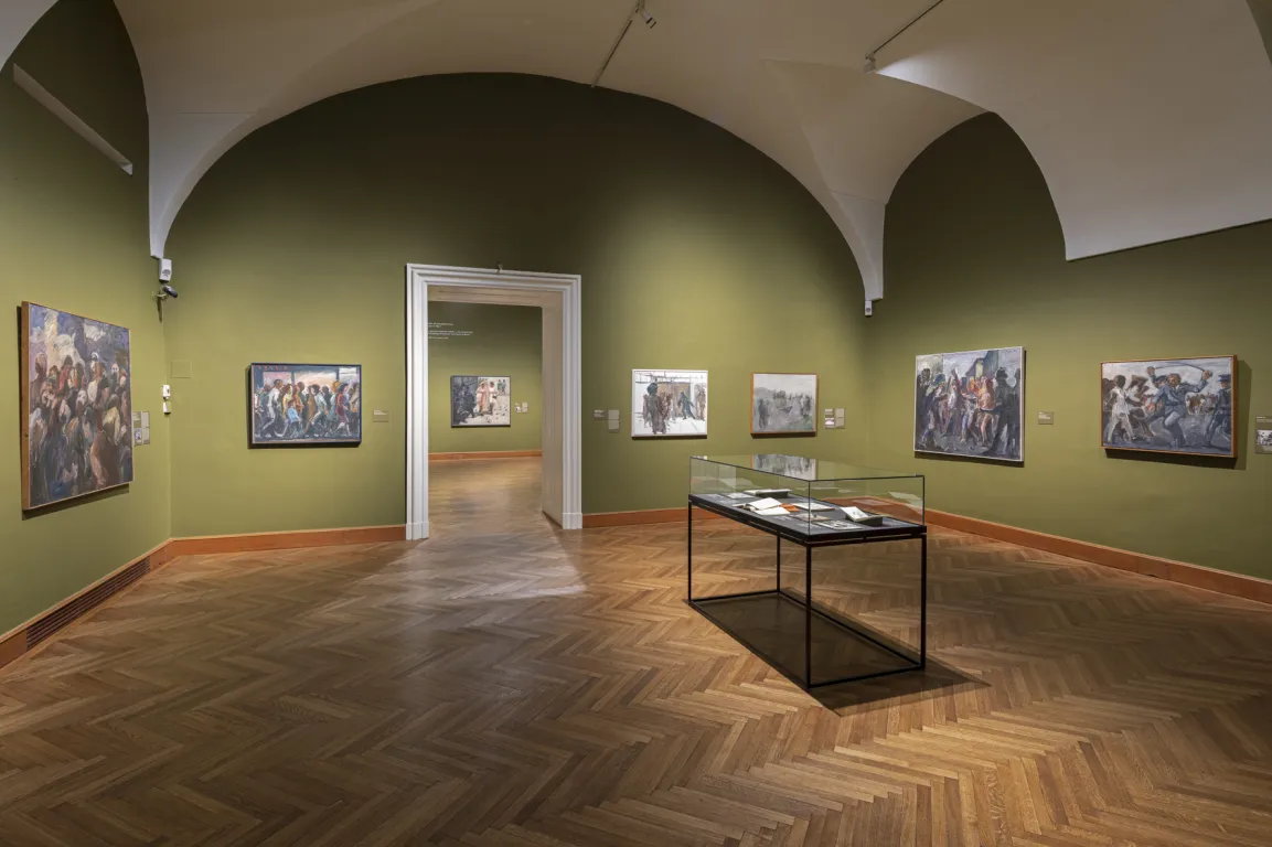 Ausstellungsraum mit gewölbter Decke und moosgrünen Wänden, darauf vage Bilder von Menschen