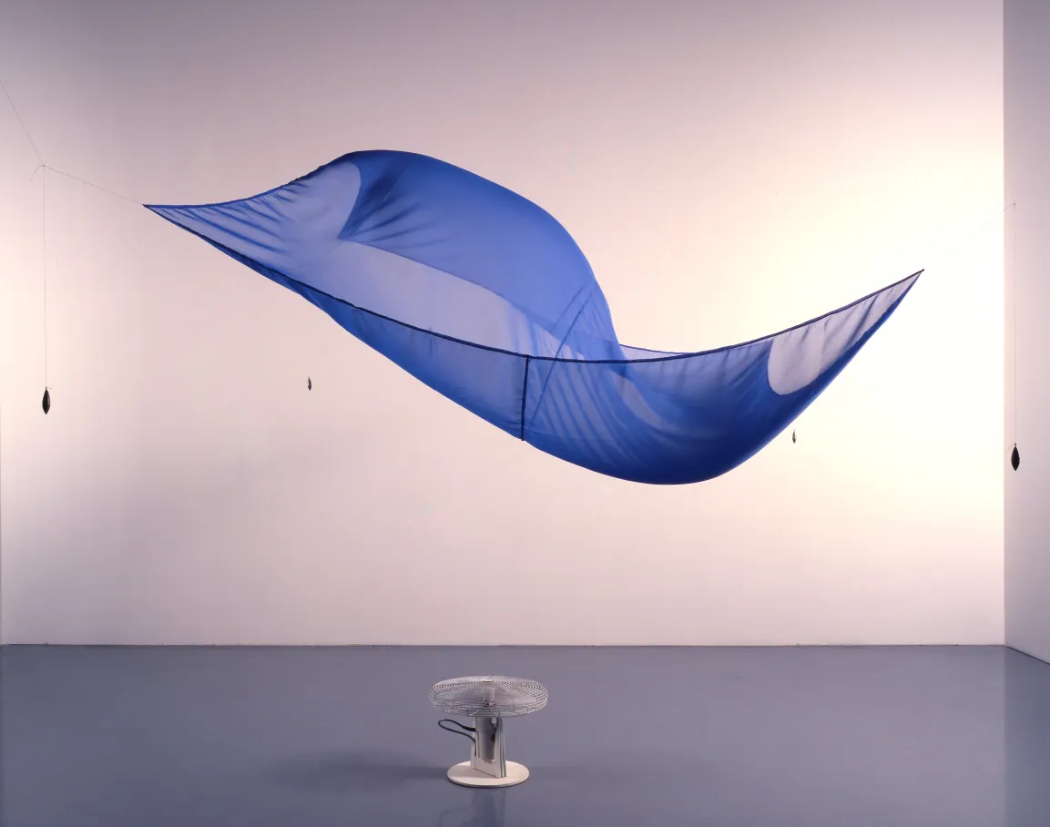 Kunstinstallation mit dem Titel Blue Sail (1964–1965) von Hans Haacke bestehend aus einem großen, halbtransparenten blauen Segel, das an dünnen Fäden aufgehängt ist. Unter dem Segel steht ein Ventilator, der Luftbewegungen erzeugt und das Segel sanft in Bewegung setzt.