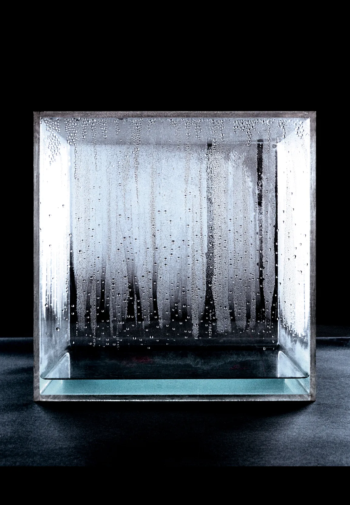 Minimalistisches Werk Großer Kondensationswürfel (1963–1967) von Hans Haacke: transparenter Würfel aus Plexiglas, der Wasser enthält. Durch natürliche Temperatur- und Feuchtigkeitsschwankungen entsteht Kondenswasser an den Innenwänden des Würfels.