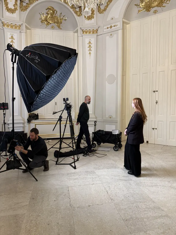 Ein Set für einen Video-Dreh im Ausstellungsraum mit einer Frau im Vordergrund und zwei Männern im Hintergrund