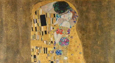 Das Bild zeigt ein Paar, das sich umarmt. Die Figuren sind mit einem goldenen, reich verzierten Hintergrund umgeben. Die beiden Personen scheint es zu umhüllen, wobei die eine Figur in einem prächtigen Gewand gekleidet ist, verziert mit Mustern und Blumenmotiven. Die Gesichter der Personen sind nah beieinander und ihre Augen sind geschlossen, was eine intime und innige Verbindung zeigt. Der untere Bereich des Bildes wird von einer üppigen vegetativen Darstellung ausgefüllt. [KI-generiert mit ChatGPT]
